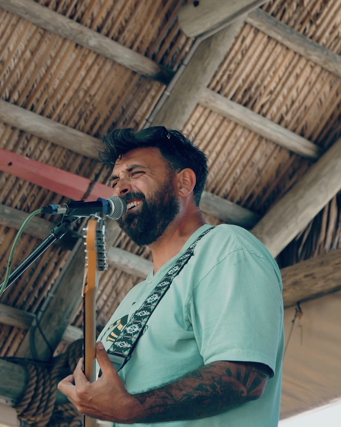 Kairo Reef singing into the microphone under a tiki roof